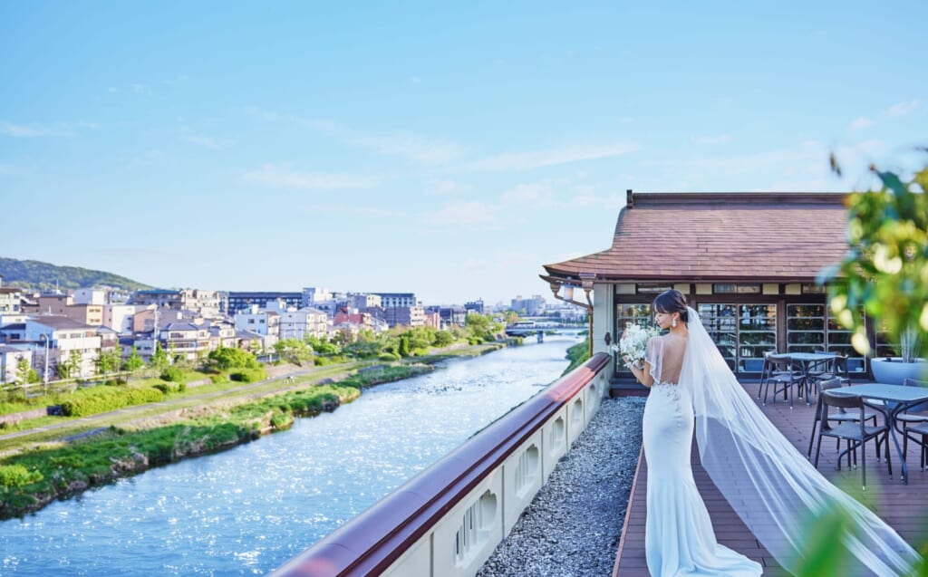 鴨川と東山の絶景を背景に最上階のテラスで誓いを立てる新婦。自然と一体化する京都らしい結婚式の一瞬。