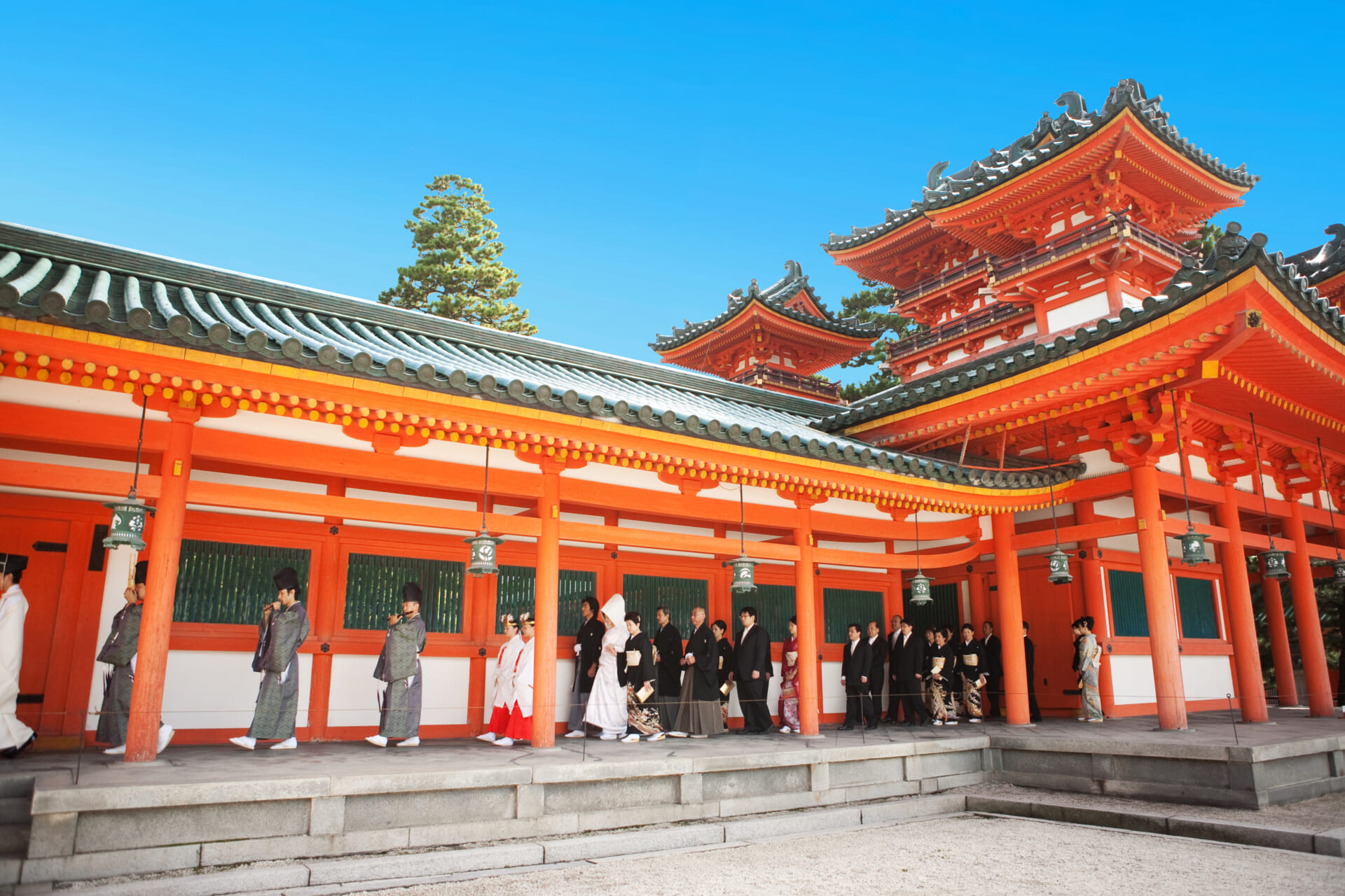 京都の神社で行われる神前式の様子。伝統的な和装姿の新郎新婦が参進の儀を進む場面