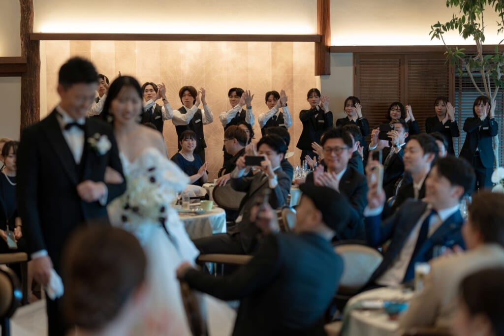 祝福を受けて入場する新郎新婦と出迎えるスタッフ